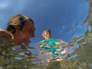 Underwater view of a father and her daughter with distorted faces having fun at the sea