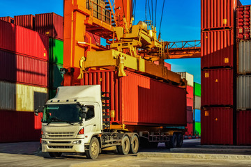 Container truck or Rubber Tired Gantry Cranes (RTG) picking up a container at yard. Port logistics, container yard operation. 