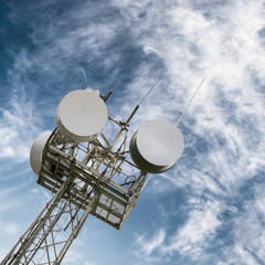 A tower with satellite dishes and radio aerials against the blue sky.