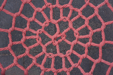 Unusual spider web woven from a red rope in the park.
