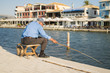 Old man fishing on the dock. Lifestyle and recreation concept.