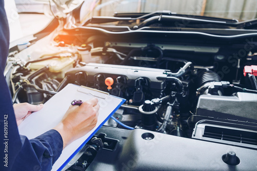 Fotografía mechanic holding a clipboard of service order working in garage