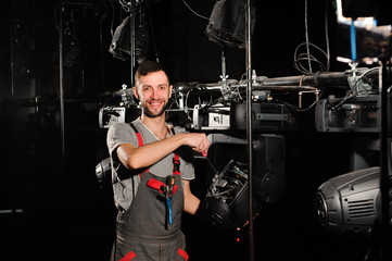 Canvas Print - The lighting engineer repairs the light device on stage