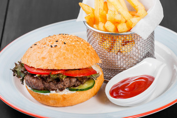 Canvas Print - Burger, hamburger with french fries, ketchup, mayonnaise, fresh vegetables and cheese on plate on dark wooden background. American fast food. Top view