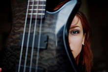 Red Haired Punk Girl Wear On Black With Bass Guitar At Abadoned Place. Portrait Of Gothic Woman Musician. Close Up Face Of Blackness Person With Guitar Riff.