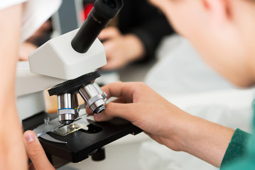 Boy at the lab looking through microscope