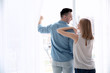 © Africa Studio - Happy couple standing near window and opening curtains