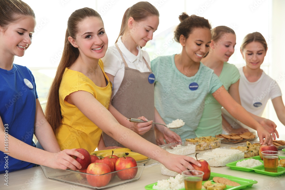 Young volunteers near table with different products indoors