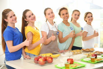 Poster - Young volunteers near table with different products indoors