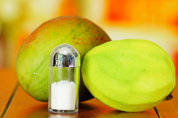 Raw and peeled mango behind salt shaker