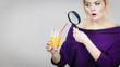 Woman holding magnifying glass investigating juice