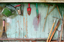Old Dirty Farm Gardening Tools, Spade, Fork And Rake On Wooden Wall