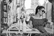 © ZoomTeam - woman sitting at the cafer on the famous street with local food markets in Italy city. BW concept