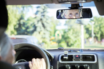 Wall Mural - Reflection of senior woman in rear view mirror