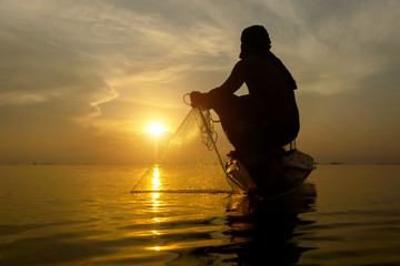 silhouette fisherman with sunset sky on the lake.