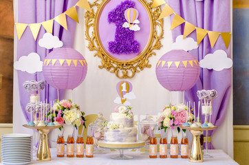 interior decoration for a child's birthday is one year in purple colors. candy, macaroon, tiered cak