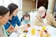 © pressmaster - Happy family sitting by table and having breakfast