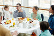 © pressmaster - Big family having talk by breakfast in restaurant
