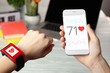 Female hands holding heart rate monitor watch and smartphone on table background