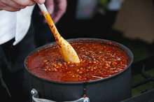 Cook Stirring A Simmering Pot Of Spicy Chili