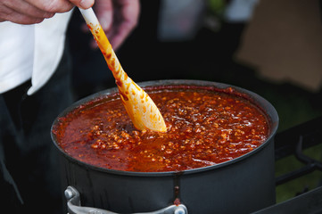 Cook Stirring a Simmering Pot of Spicy Chili