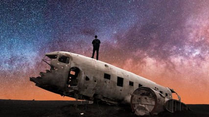 Silhouette of Man Standing on Crashed Airplane Gazes Deeply Into the Milky Way Galaxy on a Clear Starry Night Sky