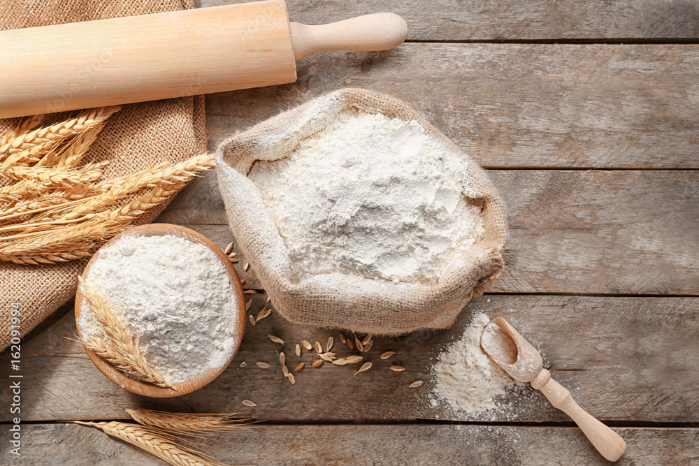 Composition with flour and kitchen utensils on wooden background
