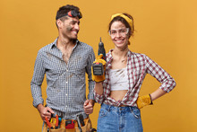 People, Occupation, Job, Profession And Relationships. Two Young Mechanics With Dirty Faces Enjoying Work Together: Man With Belt Kit Of Instruments Looking With Delight At His Colleague Holding Drill