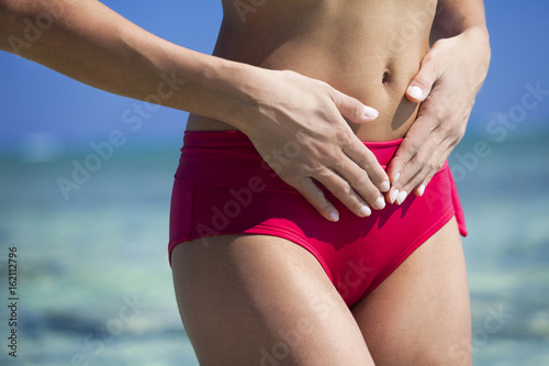 Zdjęcie XXL kobieta z rękami na brzuchu w strój kąpielowy