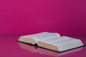 Bible and a crucifix on a pink table. Beautiful background.Religion concept.