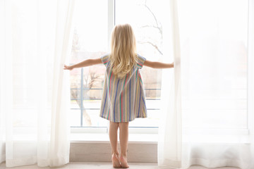 Wall Mural - Small girl opening curtains