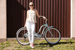 © Africa Studio - Young smiling woman with bicycle near colour wall