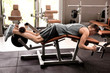 © Africa Studio - Young man performing leg curl exercise on a machine in a modern gym, focusing on hamstring strength and fitness training