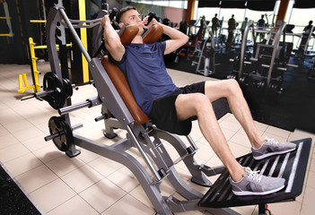 Wall Mural - Sporty young man training legs in gym