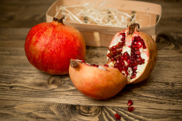 Closeup of two halves of pomegranate on old wooden board