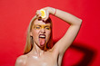 young girl squeeze yellow lemon on red background