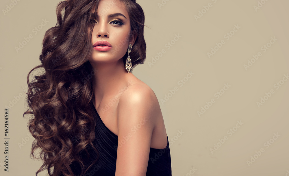 Brunette girl with long and shiny wavy hair . Beautiful model with curly hairstyle . 
 - obrazy, fototapety, plakaty 