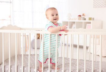 cute little baby standing in crib at home