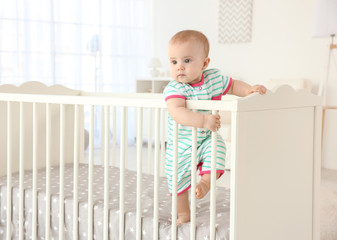cute little baby standing in crib at home