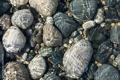 Ripples of the crystal clear shallow water surface, on a stony beach of Lake Huron, Ontario, Canada.