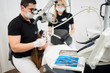 © anatoliy_gleb - Male dentist and female assistant checking up patient teeth with microscope at dental clinic office. Selective focus on the dental tools. Medicine, dentistry and health care concept. Dental equipment