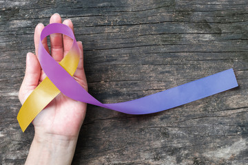 Wall Mural - Bladder cancer awareness marigold blue purple ribbon  (isolated with clipping path)  symbolic color on helping hand support