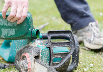 Handyman replenishes the oil in chain saw for chain maintenance