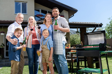 Wall Mural - big happy family with beverages looking aside while having barbecue together