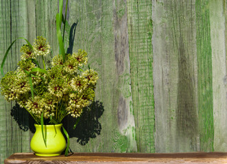 Vintage background. Ceramic vase light yellow with wildflowers on a background of old green wooden wall