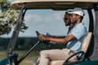 © LIGHTFIELD STUDIOS - smiling multiethnic friends talking while riding golf cart