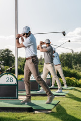 Wall Mural - group of focused gstylish playing golf together at golf course