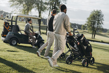 Multiethnic Golf Players With Golf Bags And Golf Cart Spending Time Together