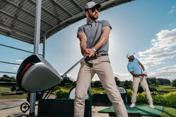 Wall Mural - Two young golfers with clubs playing golf together