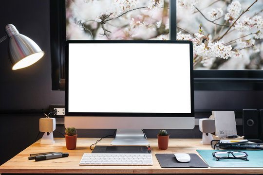Graphic designer's workspace equipped with a pen tablet, a computer and white screen for text with beautiful sakura flower from the window